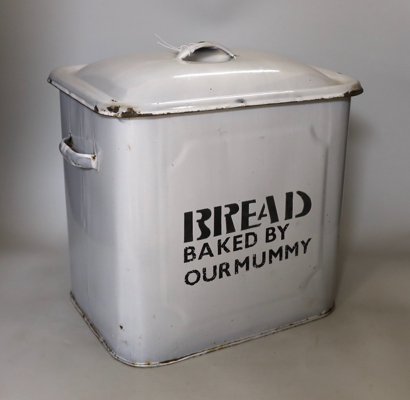 A vintage white enamel bread bin and cover, printed “Bread Baked By our Mummy”